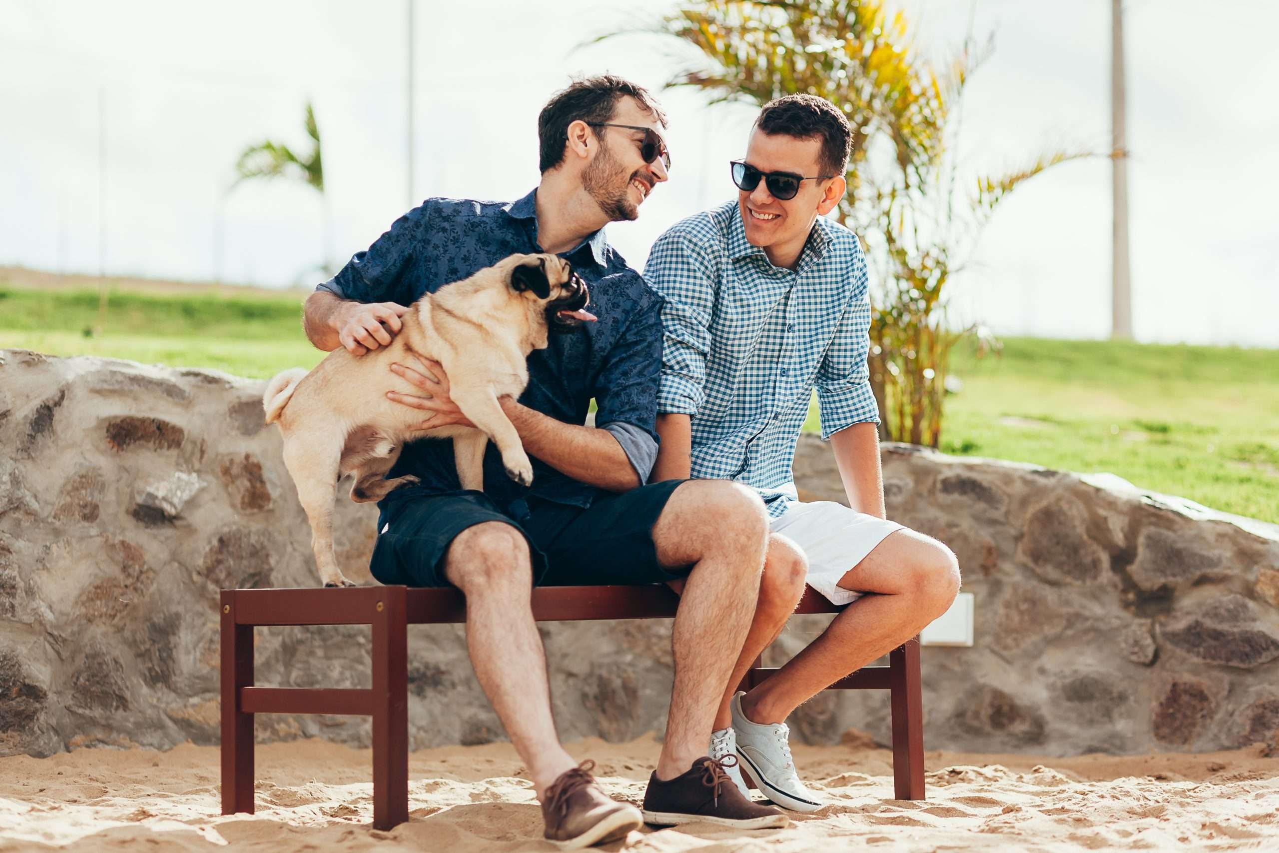Two men smiling with a dog.